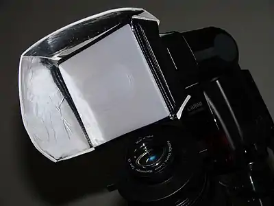 A more formal diffuser filter over a camera flash, flanked by reflectors