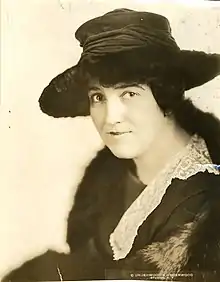 A young white woman with dark hair, wearing a dark brimmed hat and a lace collar.