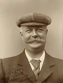 Head and shoulders portrait of a man in his fifties with moustache wearing a hat