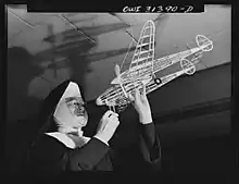 Washington, D.C. Sister Aquinas, "flying nun," applying a little glue to the model P-38 which hangs from the ceiling of her classroom at Catholic University. A veteran of fifteen years' teaching experience, the Sister is giving a summer Civil Aeronautics Authority course for instruction