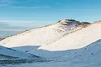 "The site in winter, with snow covering the mountains and the summit region."