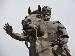 Skanderbeg with right hand raised in greeting pose