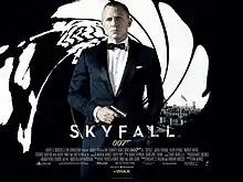 The poster shows James Bond wearing a tuxedo and holding a gun, standing in front of an image that looks like it was taken from the inside of a gun barrel, with the London skyline visible behind him. Text at the bottom of the poster reveals the film title and credits.