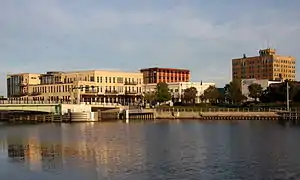 Manitowoc River, near where it enters Lake Michigan, reflecting the skyline of downtown Manitowoc, with the U.S. 10 highway bridge at left.