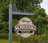 handpainted sign reading "Welcome to Sobieski, witamy"