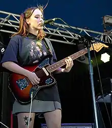 Soccer Mommy playing guitar and singing onstage