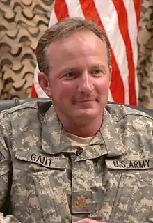 Man in military uniform with American flag behind him