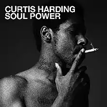 Black-and-white photograph of a shirtless African-American man (Harding) smoking a cigarette with the text "Curtis Harding" and "Soul Power" in a white font at the top-left corner