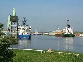 Large ships on calm water with an old coal tippler crane on the dockside