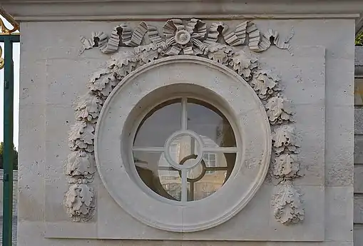 Oculus of the Petit Trianon (Versailles, France), with a ribbon at the top and two festoon-derived hanging ornaments