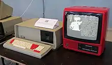 A computer in a red case with a separate monitor and keyboard. The monitor is displaying a vector graphic of a wave.