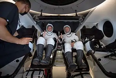 Robert Behnken, left, and Douglas Hurley are seen inside SpaceX Crew Dragon Endeavour being greeted by SpaceX medical director Anil Menon on board GO Navigator.