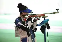 Colour photograph of a woman firing a rifle from the standing position.