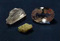 An almost colorless kunzite crystal (upper left), a cut pale pink kunzite (upper right) and a greenish hiddenite crystal (below) (unknown scale)