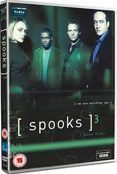 A DVD boxset cover in a dark green background with the logo "[ spooks ]3. At the top half there are four people standing. From left to right, a short blonde-haired woman, a black British man, and two Caucasian males wearing a shirt and jacket.
