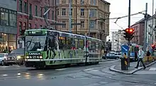 A tram with advertisements at a busy intersection