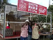 Glass building with red-and-white sign and three people in front