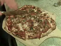 A St. Louis–style pizza being sliced into squares