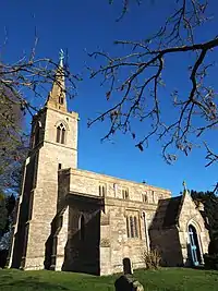 A stone church seen from the south with, from the left, a tower with a steeple, the nave with clerestory and porch, and to the right the chancel