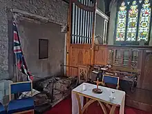 View looking East within the Beafort chapel. The remains of the three tomb effigies damaged by Parliamentarians in during the English Civil War are on the floor in front of the organ, between two simple railings, with the remains of a canopy visible on the wall.