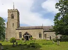 ancient stone village church with tower, in graveyard surrounded by trees