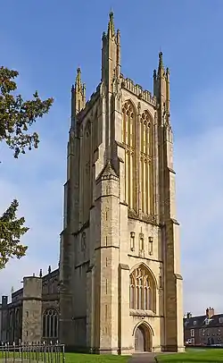 Decorated and buttressed yellow stone tower.