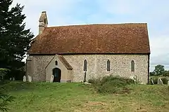 A small simple church with a west bellcote seen from the south
