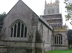 Stone building with arched window. Square tower surrounded by scaffolding.