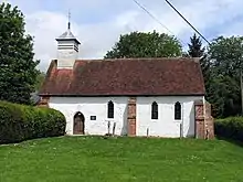 A small, simple, white church, with a red tiled roof and a wooden bellcote