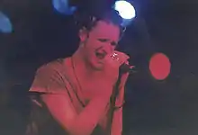 A male singer, Layne Staley, performs onstage with Alice in Chains. He holds the microphone with both hands and his eyes are closed as he sings.
