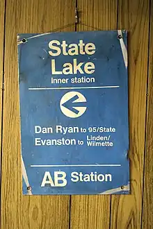 A blue metal sign, worn at the corners, with the following text in white Helvetica font: "StateLakeInner station←Dan Ryan to 95/StateEvanston to Linden/WilmetteAB Station"