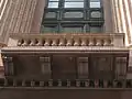 A close-up of the building's distinctive terracotta and pink granite façade.