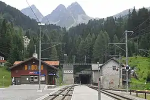 Two-story building with gabled roof next to double-track railway line entering a tunnel