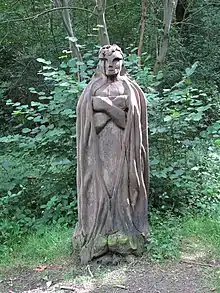 A wooden statue of a man in a woodland