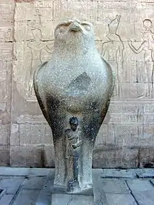 One of two statues of the falcon god Horus behind a smaller depiction of Caesarion at the Temple of Edfu in Edfu, Upper Egypt