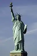 A crowned, robed woman holding aloft a torch