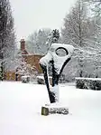 The statue outside the old porter's lodge in snow, "Achaean" by Barbara Hepworth.