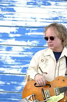 Steve Ripley wearing sunglasses, with a guitar
