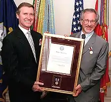 Secretary of Defense William S. Cohen presents a framed citation accompanying the medal given to Steven Spielberg.