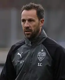 Steve Cherundolo wearing a black-and-gray jacket with the logos of VfB Stuttgart and Puma.