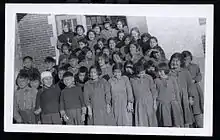 Group photo of Indigenous students in front of a brick building. A nun is visible in the back row.