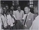 Naipaul attended the government-run Queen's Royal College (QRC), a high school, Port of Spain from 1942 to 1950.  Shown here are some older students at QRC talking to a visitor in 1955.