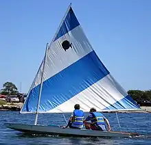 Picture of a Sunfish (small boat) with two people sailing it.