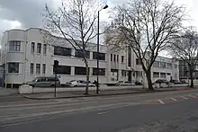 Long white building in winter, with trees in front