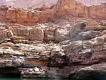 Tan- to cream-colored layer cliff face above water