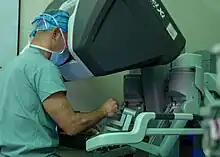 A surgeon sits with his face surrounded by a computer terminal