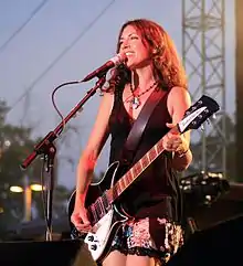 A woman playing a black and white electric guitar