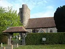 A flint church with a square tower and a circular stair turret, and red tiled roofs