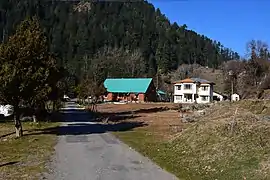 Two buildings and a tall birdhouse on a wooded mountainside