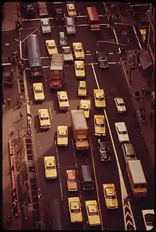 Aerial view of the Herald Square area of mid-town Manhattan, near the intersection of 34th Street and Broadway. Traffic is nearly gridlocked, as each of the five the lanes are filled by cars and trucks. Of the vehicles shown in the photograph, 16 are yellow-colored taxicabs, but only three of the those are Checker Model A11 taxicabs.